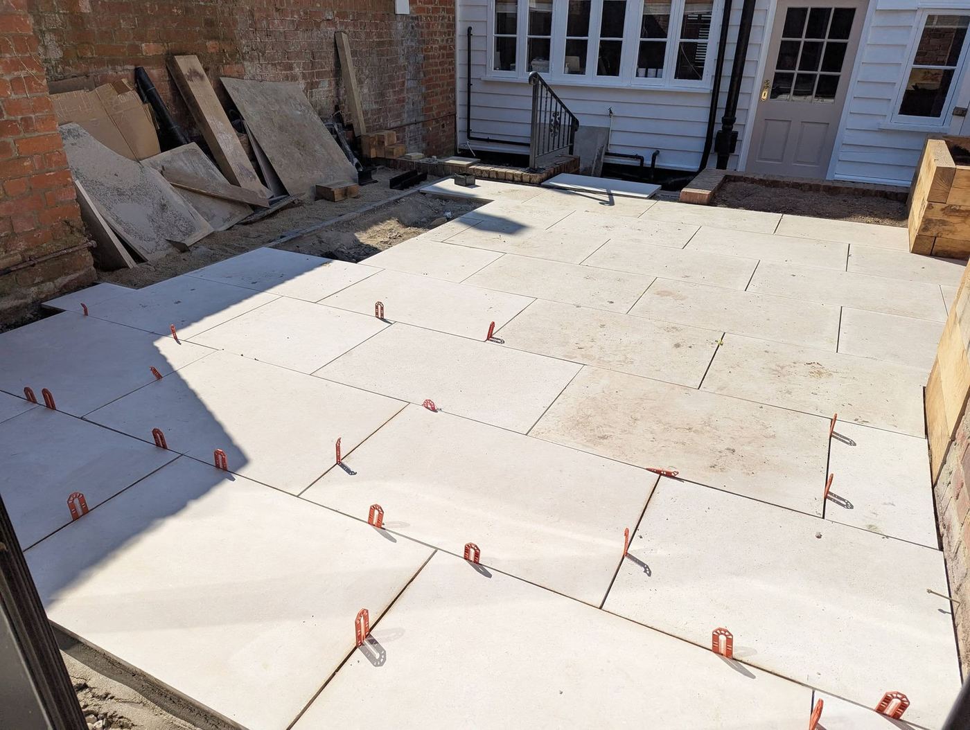 Porcelain paving being levelled with red levelling clips in the sun
