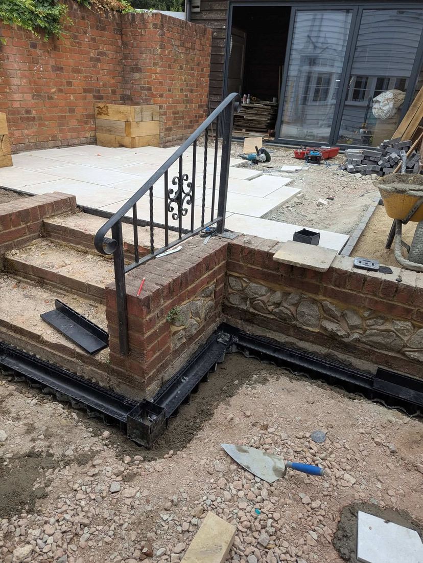 Channel drainage being installed around brick steps before paving