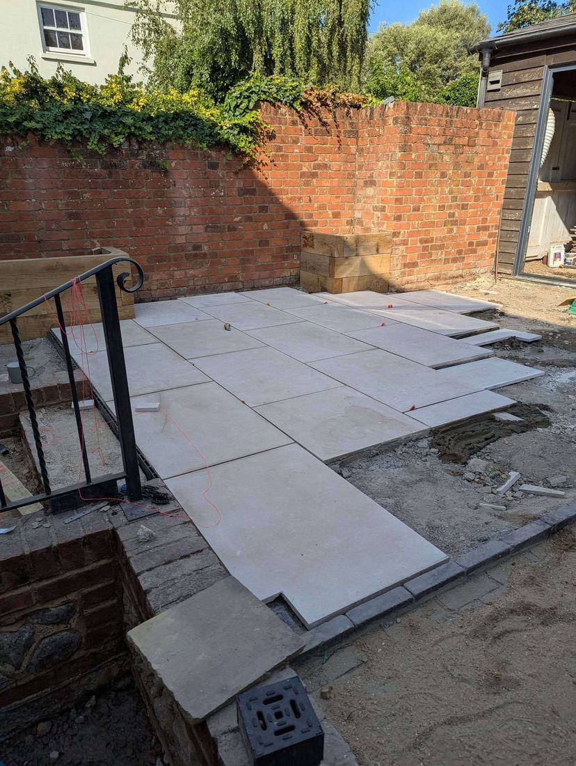 Porcelain slabs set out with a string line beside oak sleeper planters