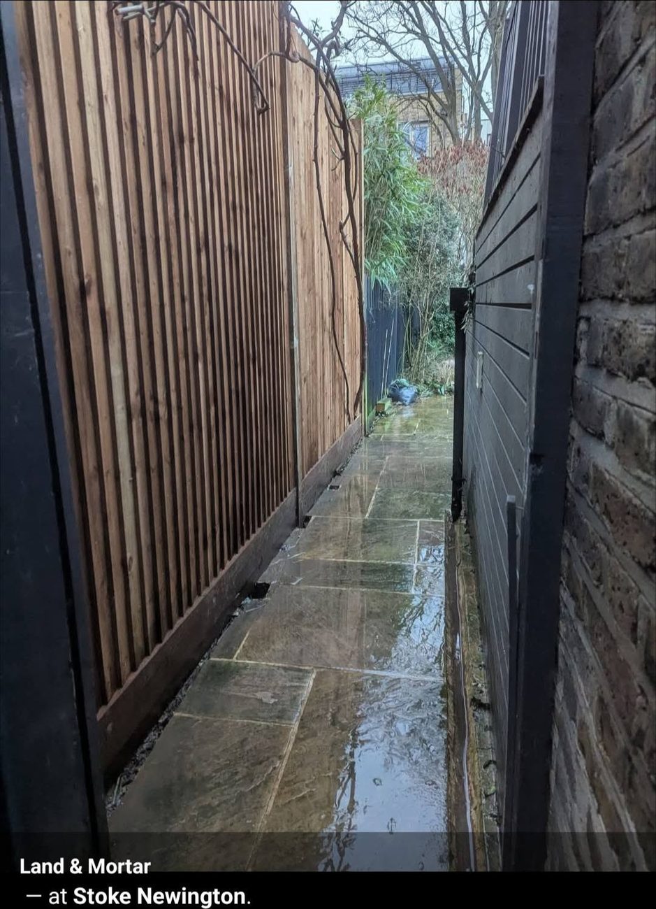 Vertical slatted screen fence along a narrow sandstone path