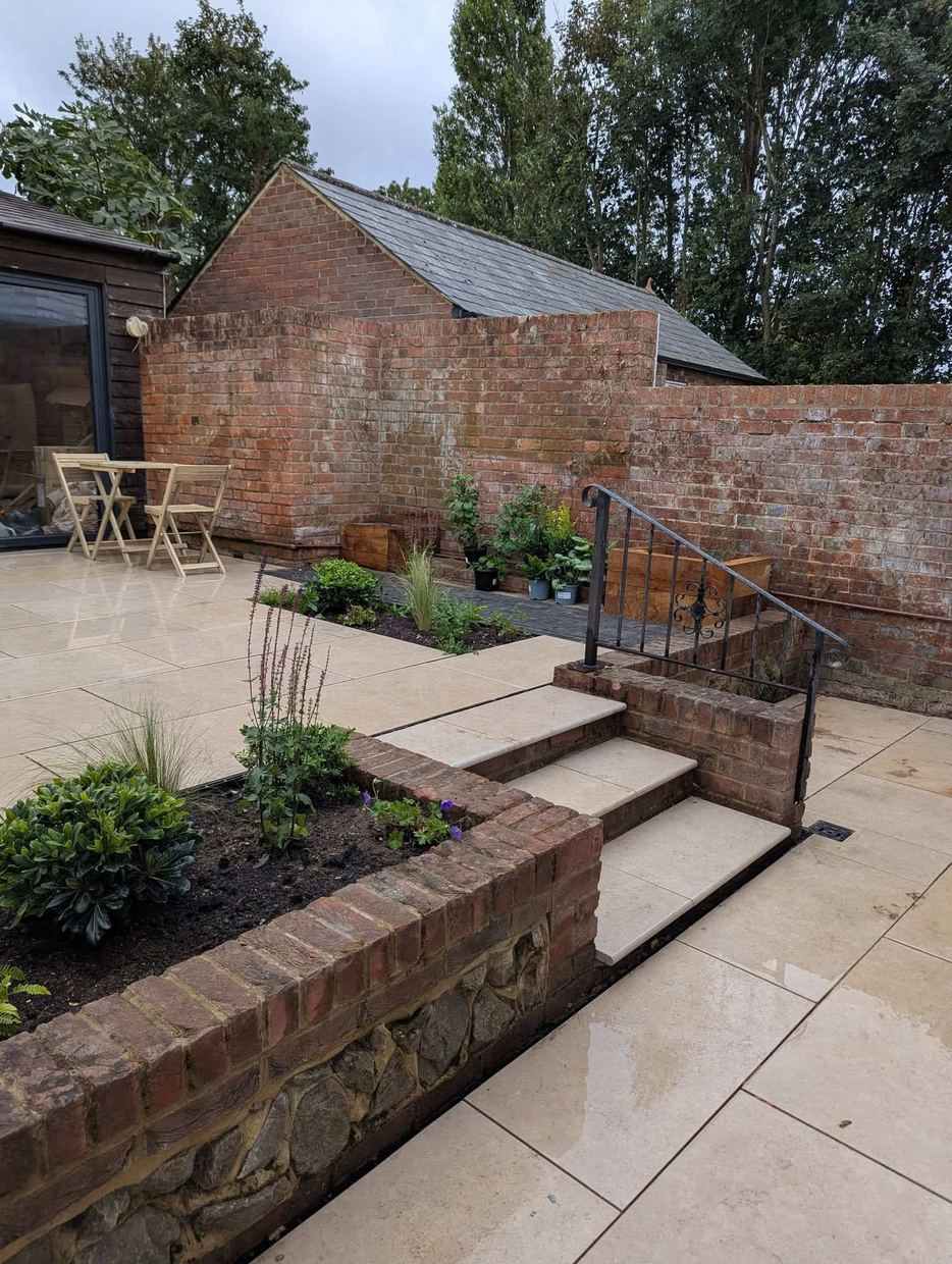 Brick and flint raised beds with stone-topped steps and iron railing