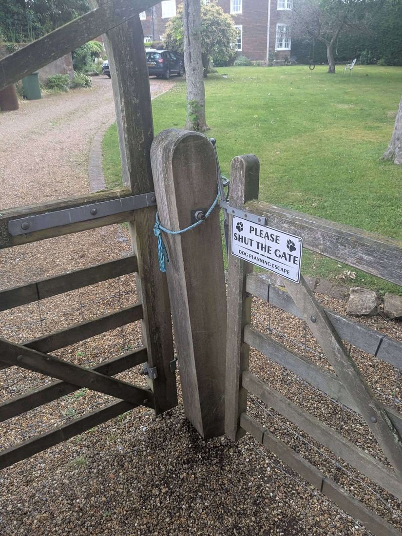 Old weathered rounded gate post with the gate tied shut by rope